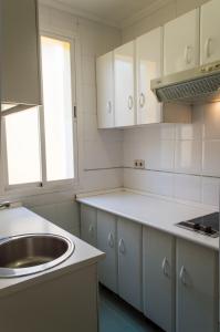 una cocina con armarios blancos y fregadero en For You Rentals reina sofia apartment DF21, en Madrid