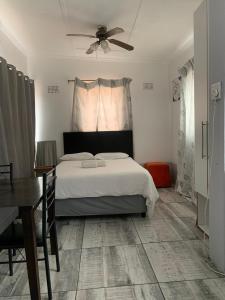 a bedroom with a bed and a table and a ceiling fan at Let Us accommodation in East London +25 photos