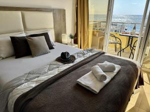 a bedroom with a bed with towels and a balcony at Apart-Hotel Saraj in Dobra Voda