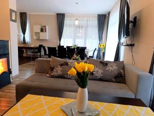 a living room with a couch and a table with yellow flowers at "Бадевски рай" Къща за гости ВЯРА in Elena