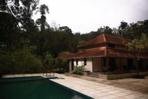 a house with a swimming pool in front of a house at Aelam Acres in Chillithodu