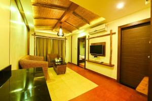 a living room with a television and a table and chairs at Hotel Sepoy Grande in Mysore