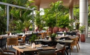 a restaurant with tables and chairs and plants at Radisson Blu Hotel Lusaka in Lusaka