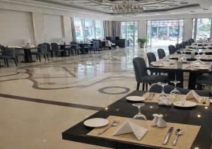 a dining room with tables and chairs and a chandelier at Carawan Al Khaleej Hotel Olaya in Riyadh
