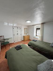 a room with two green beds and a chair at Casa Rural SERAGAL in El Bonillo