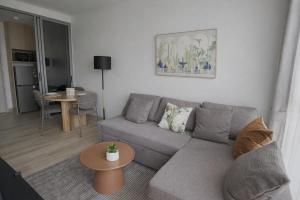 a living room with a gray couch and a table at Skypark Celeste with stunning golf course view in Laguna Phuket