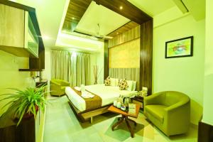 a hotel room with a bed and a green chair at Hotel Sepoy Grande in Mysore +14 photos