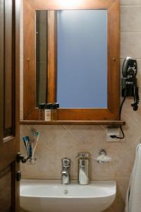 a sink in a bathroom with a mirror and a phone at Guesthouse Armakas in Kalavrita