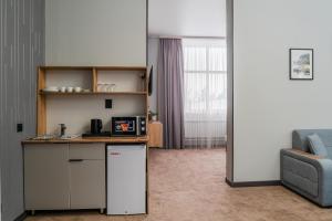 a small kitchen with a refrigerator and a couch at Nord Karakol Hotel in Karakol