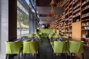 a restaurant with green chairs and tables and bookshelves at Hotel SB Plaza Europa in Hospitalet de Llobregat