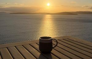 a coffee cup sitting on a wooden table near the water at Taigh Druim in Elgol