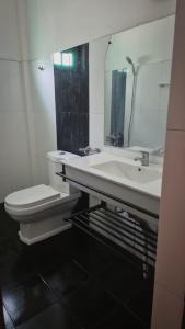 a bathroom with a sink and a toilet and a mirror at Pearl City Resort in Tissamaharama +7 photos