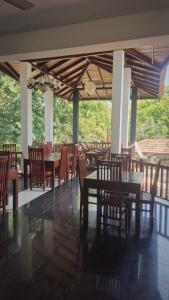 a dining room with tables and chairs in a building at Pearl City Resort in Tissamaharama