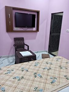 a bedroom with a bed with a tv on the wall at Ayodhya Stay in Ayodhya