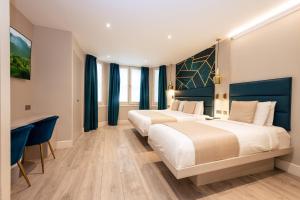 two beds in a hotel room with blue curtains at NOX Kensington in London +174 photos