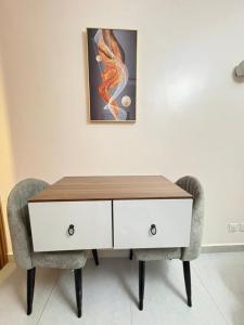 a table with two chairs and a painting on the wall at Pinecourt Luxury Apartment in Ikate