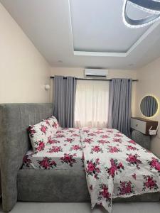 a bedroom with a bed and a couch with flowers at Pinecourt Luxury Apartment in Ikate