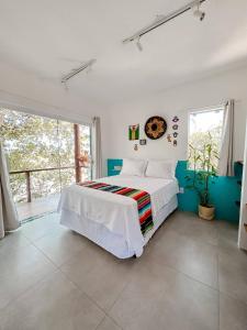 a white bedroom with a bed and a large window at Vila Real Apartamentos in Itacaré +56 photos