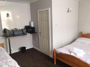 a bedroom with two beds and a door with a microwave at Richmond House Hotel in Southport