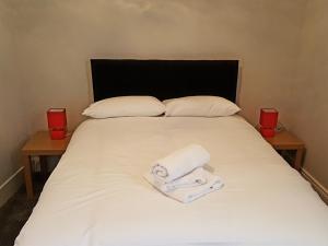 a bed with two towels on it with two tables at Richmond House Hotel in Southport