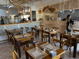 a woman standing in a restaurant with tables and chairs at Atlas Apartments Ibiza in Santa Eularia des Riu