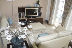 a living room with a white couch and a tv at Ferienwohnung Gesine 2 in Nienhagen