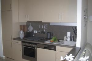 a kitchen with white cabinets and a stove and a sink at Ferienwohnung Gesine 2 in Nienhagen