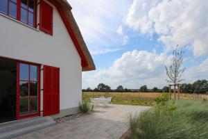 a white building with red doors and tables and a field at FH Wiesenkieker in Güstow