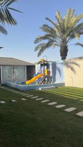 a playground in front of a house with a palm tree at شاليهات وقت الفرح in Riyadh