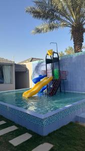 a water slide in a pool with a palm tree at شاليهات وقت الفرح in Riyadh +18 photos
