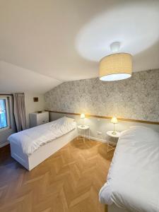 a bedroom with two beds and two tables with lamps at La petite maison orange in Koenigsmacker