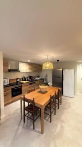 a kitchen with a wooden table with chairs and a refrigerator at La petite maison orange in Koenigsmacker