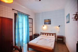 a bedroom with a bed with white sheets and blue curtains at Kastri in Panormos Skopelos
