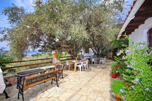 a patio with a table and benches and trees at Kastri in Panormos Skopelos