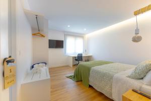 a white bedroom with a bed and a desk at Lar de Sefa 15 in Redondela +49 photos
