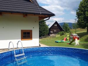 a swimming pool in the backyard of a house with a playground at Chalupa Šalalandia in Zázrivá
