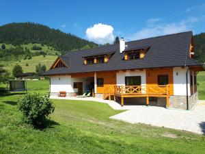 a house with a black roof on a green field at Chalupa Šalalandia in Zázrivá