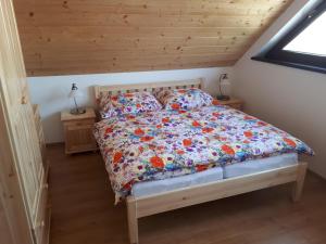 a bedroom with a bed with a floral comforter at Chalupa Šalalandia in Zázrivá +37 photos