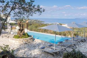 a pool with chairs and umbrellas and the ocean at Three Stones Villas by Rodostamo Collection in Kassiopi