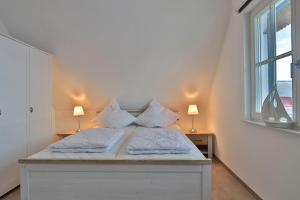 a bedroom with a bed with white sheets and pillows at FH Seeschwalbe in Niendorf
