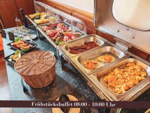 a buffet with several trays of food on a table at Villa Dora Petit Hôtel in Bad Reichenhall