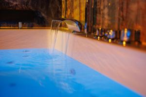 a bath tub with a water fountain at Suite Dark Luxe avec Écran géant de cinéma et jacuzzi in Clary