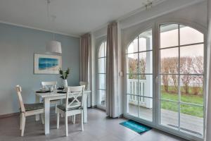 a dining room with a white table and chairs and windows at Friederike 2 in Nienhagen +33 photos