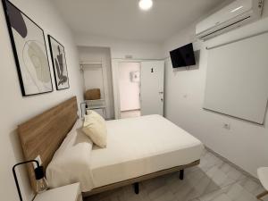 a white bedroom with a bed and a flat screen tv at Hostal Merino Jédula in Jedula