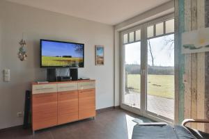 a living room with a flat screen tv on a wooden dresser at Sommersprosse in Börgerende-Rethwisch +17 photos