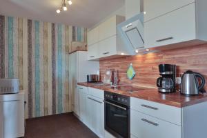 a small kitchen with white cabinets and a sink at Sommersprosse in Börgerende-Rethwisch