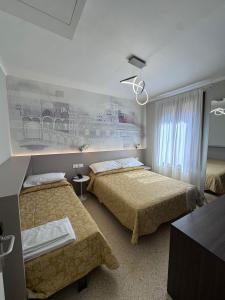 a bedroom with two beds and a painting on the wall at Hotel Adriatico in Venice
