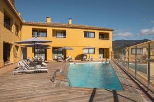 a pool with chairs and umbrellas next to a building at Feelathome Vil-la Romana in Tossa de Mar