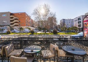 a patio with tables and chairs on a balcony at Four Side Hotel in Prishtinë