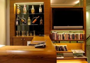 a living room with a television and a book shelf with liquor bottles at Hotel Studio Estique in Pune